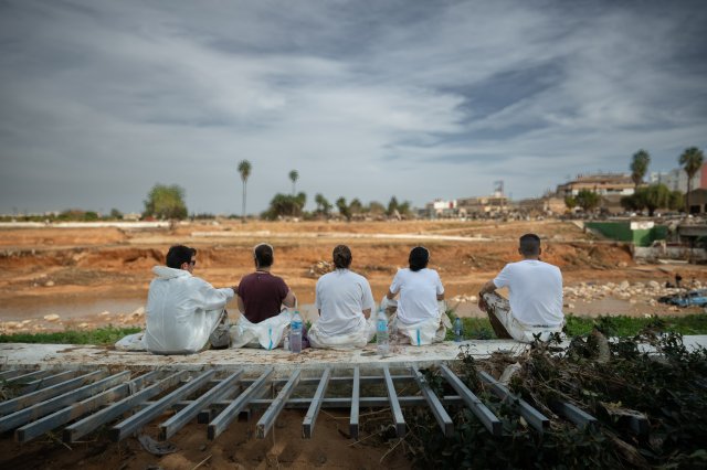 Voluntarios en su descanso mirando el canal. A la altura del puente de la estación, Paiporta